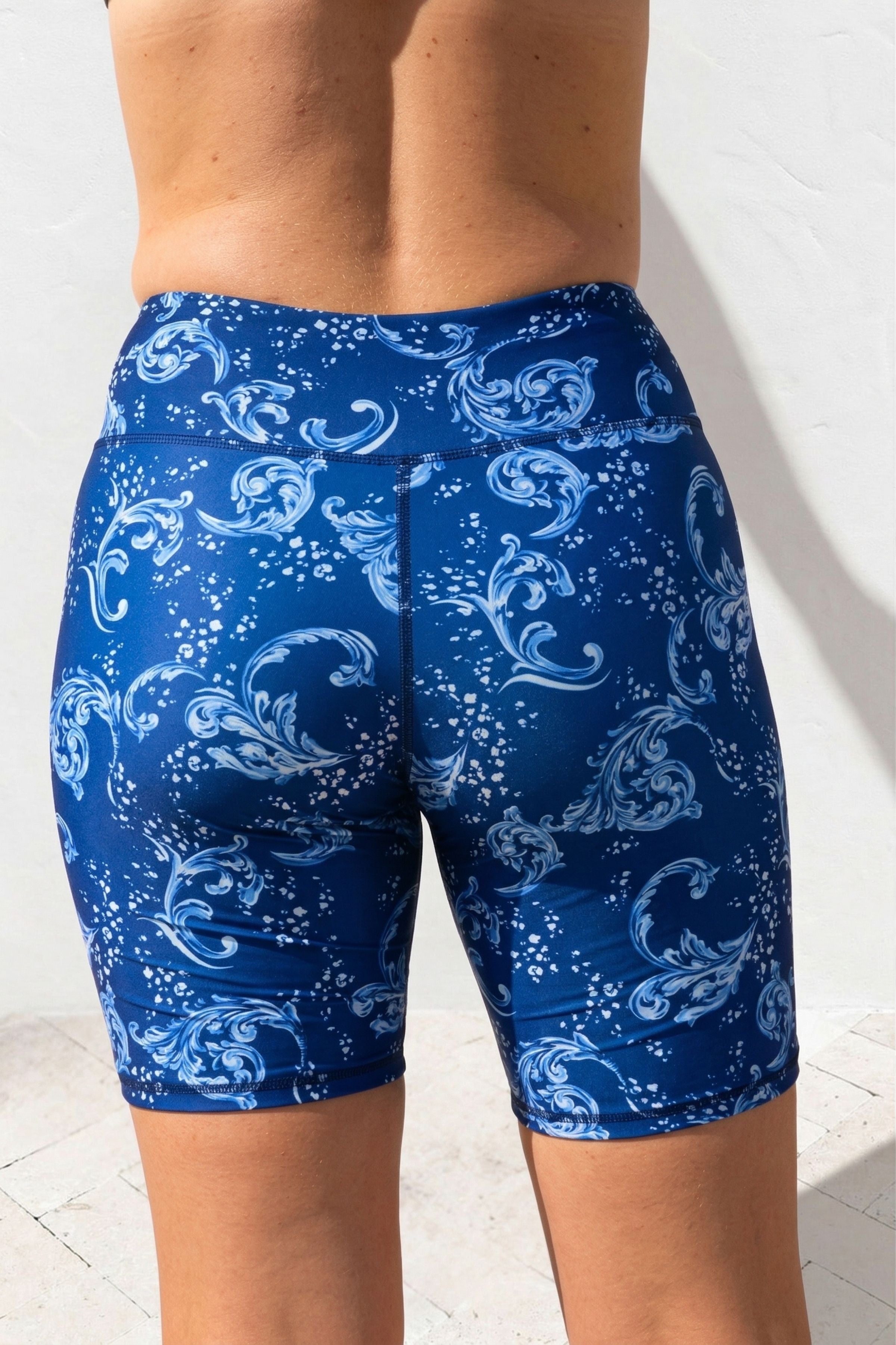 Blue swim shorts with white patterns on a white background