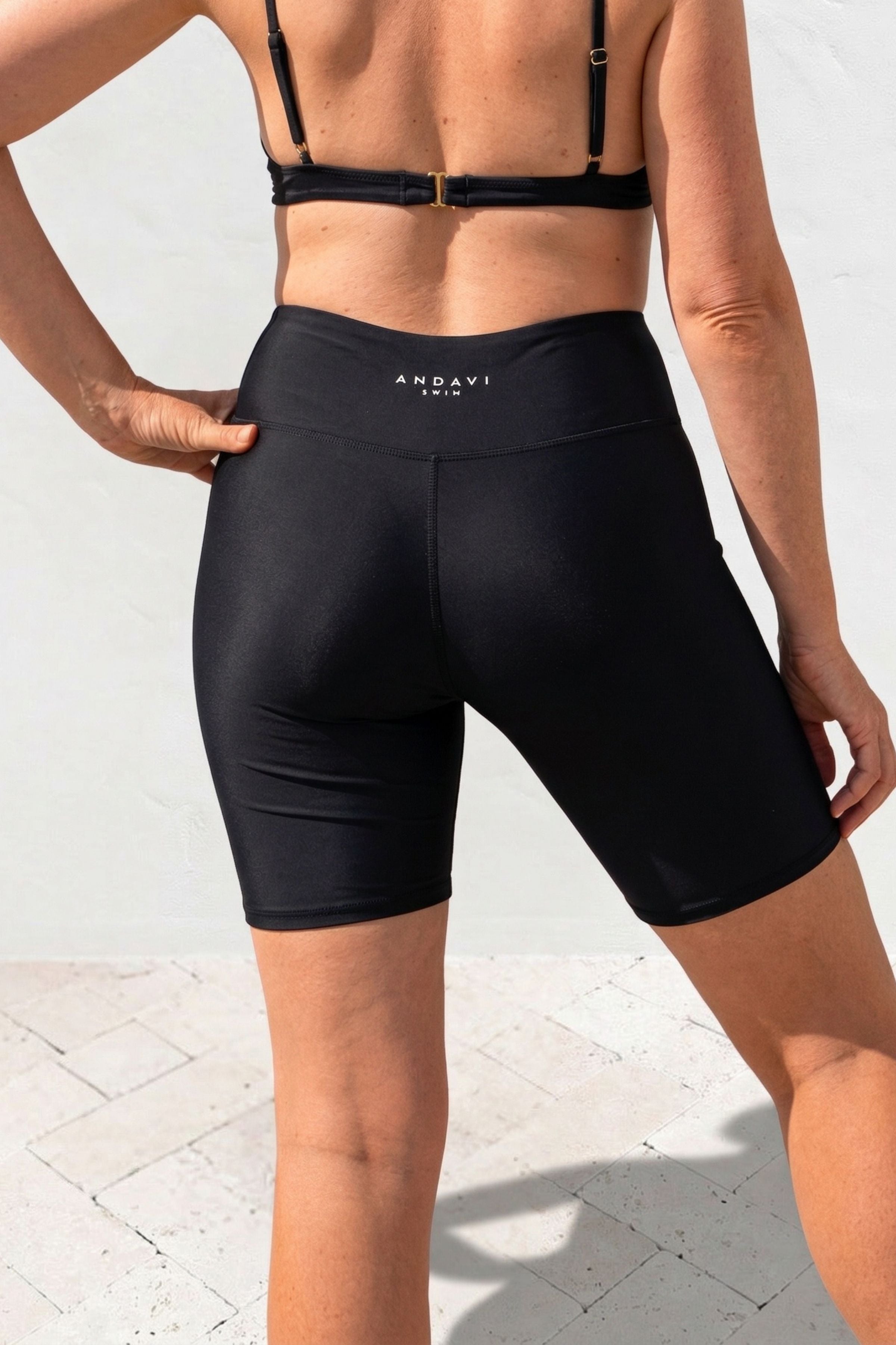 Person wearing black athletic shorts with a visible brand logo on a light background