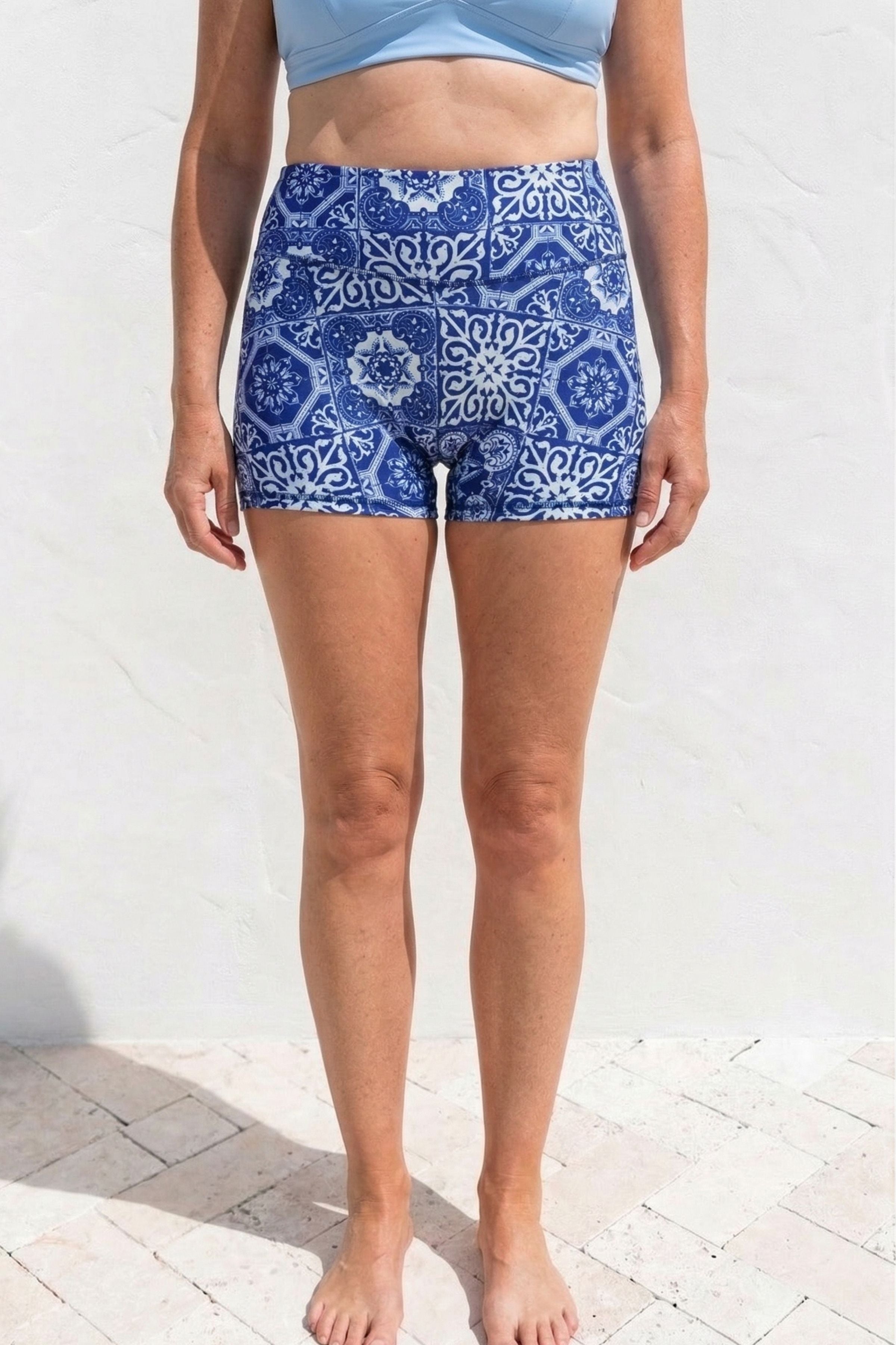 Person wearing blue patterned shorts on a white background