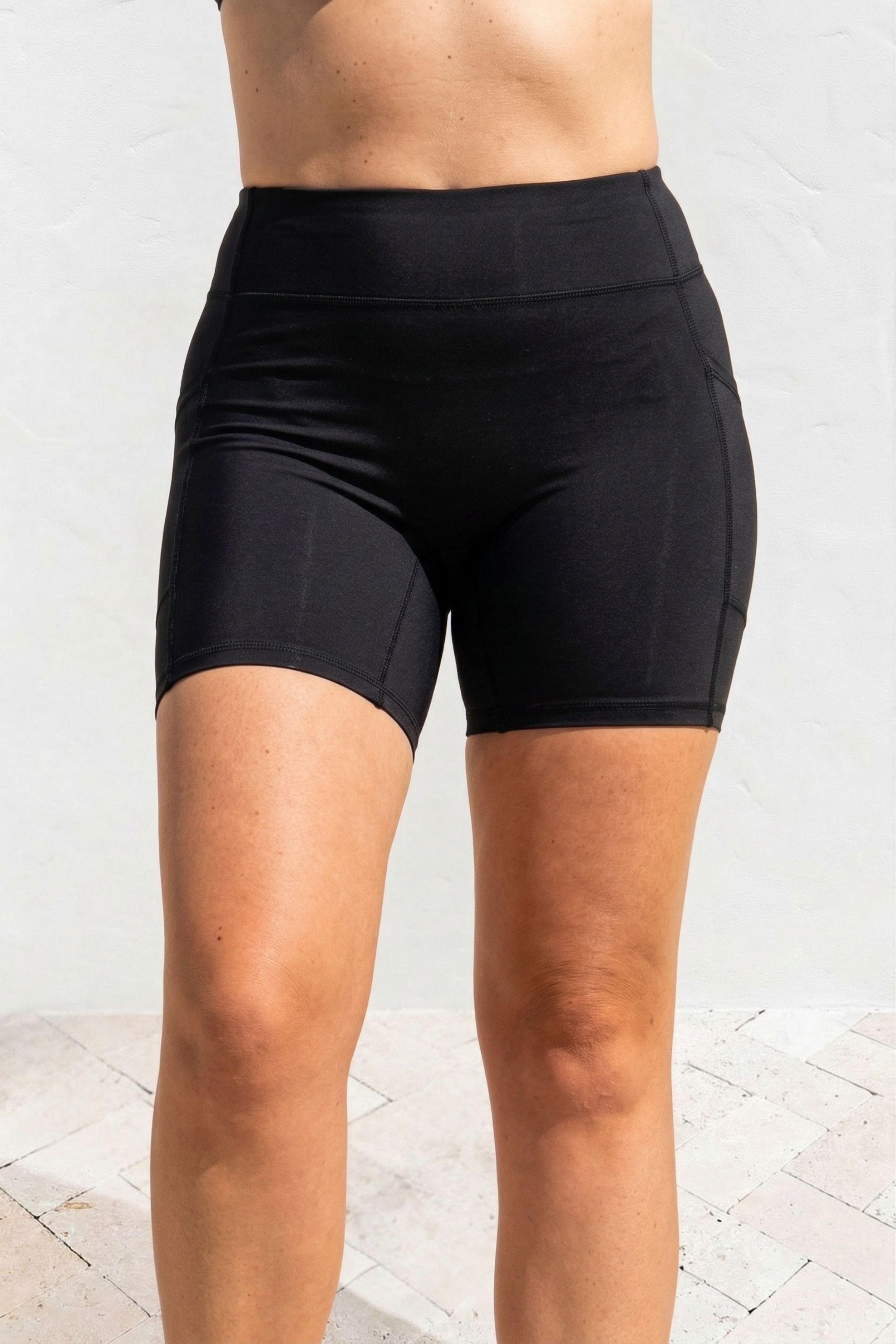 Black athletic shorts worn by a person on a light background