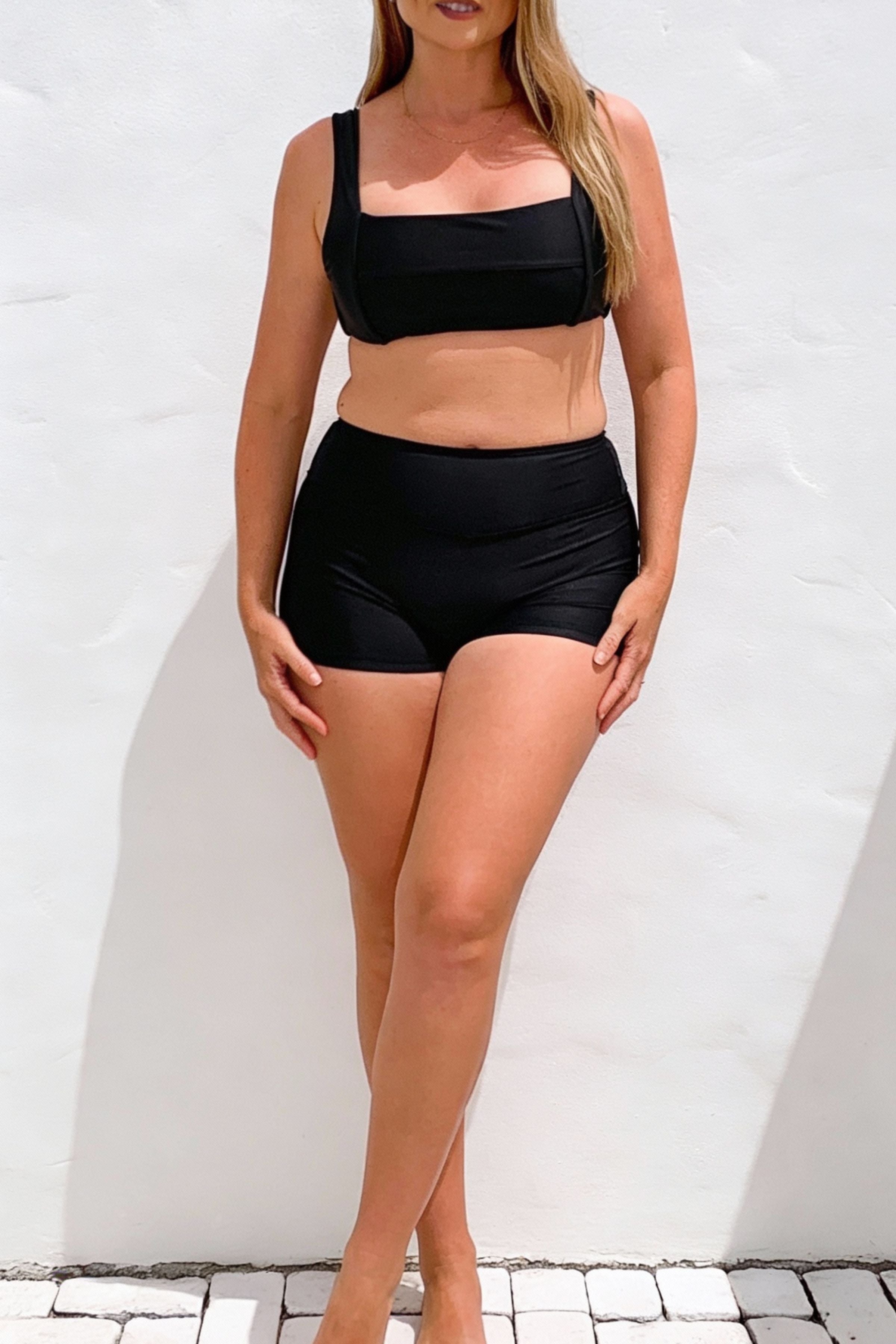 Woman wearing a black bikini set against a white background