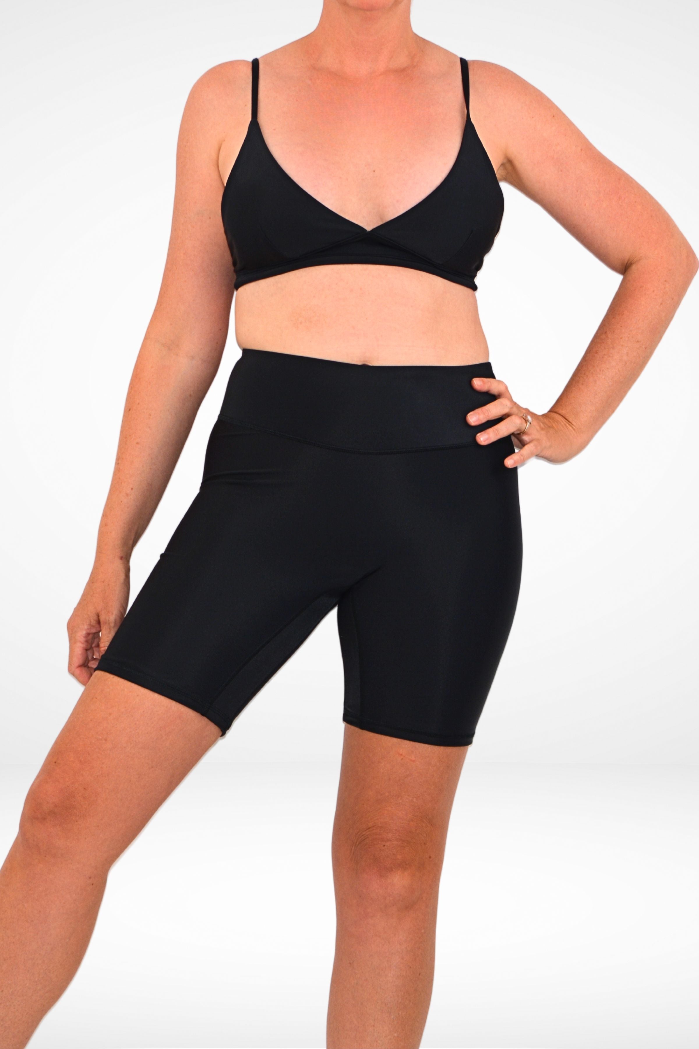 model wearing andavi black long line compression swim shorts with black triangle bikini top