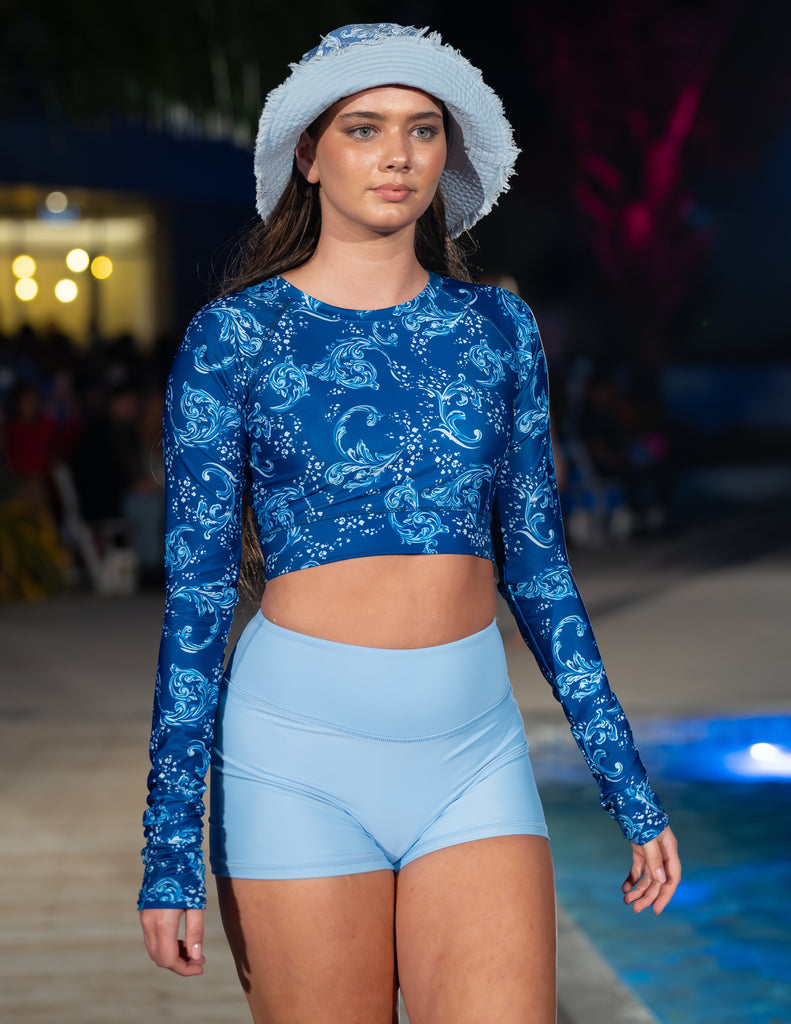 women on catwalk wearing bucket hat and blue and white crop rash guard with light blue shorts