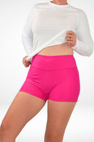 model wearing white rash guard and dark pink swim active shorties