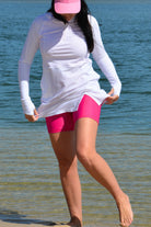 model wearing andavi swim hot pink swim shorts and white long sleeve andavi swim rash guard and matching hot pink andavi swim pink cap