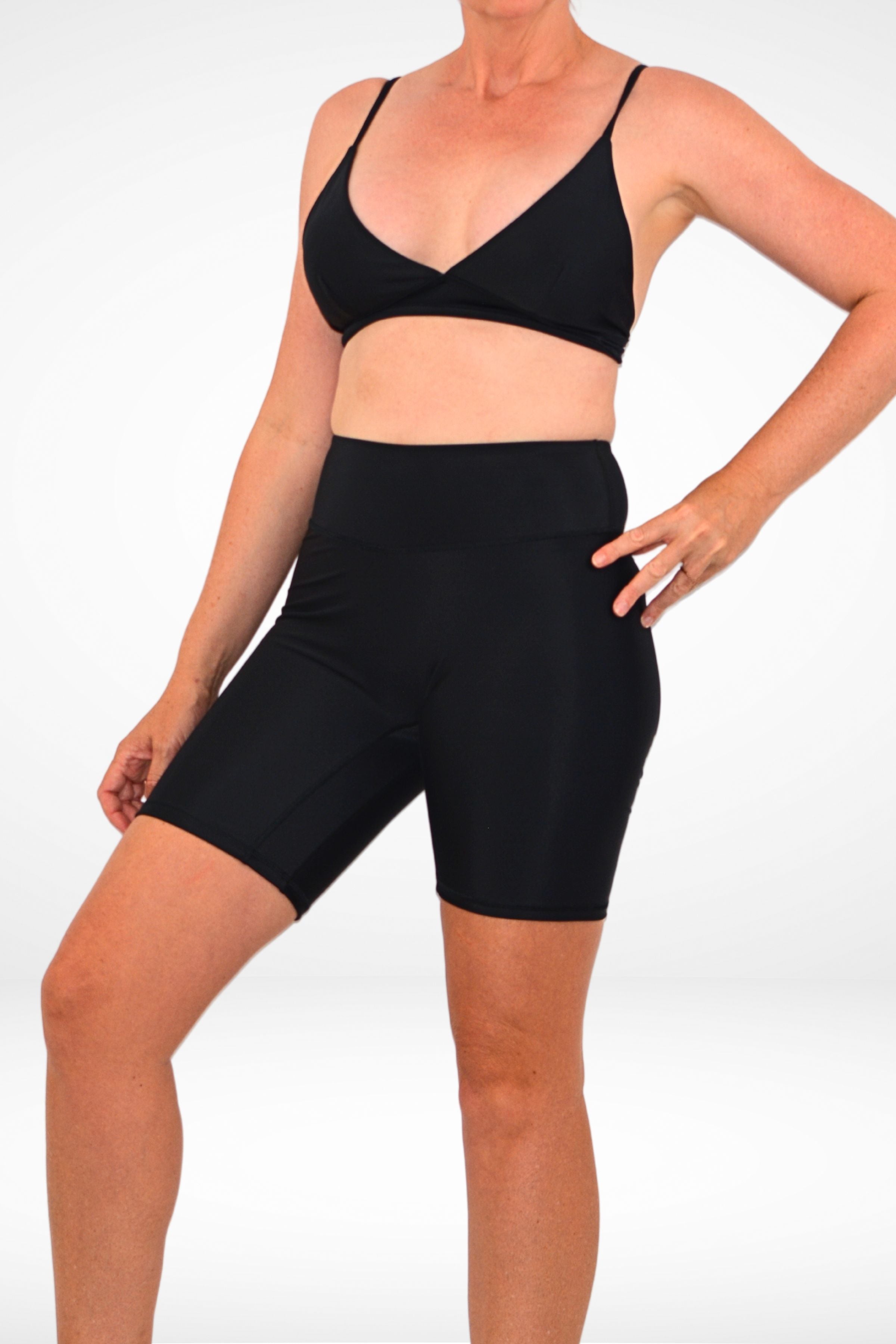 model wearing black swim short set with black triangle bikini top and black long line swim active bike shorts