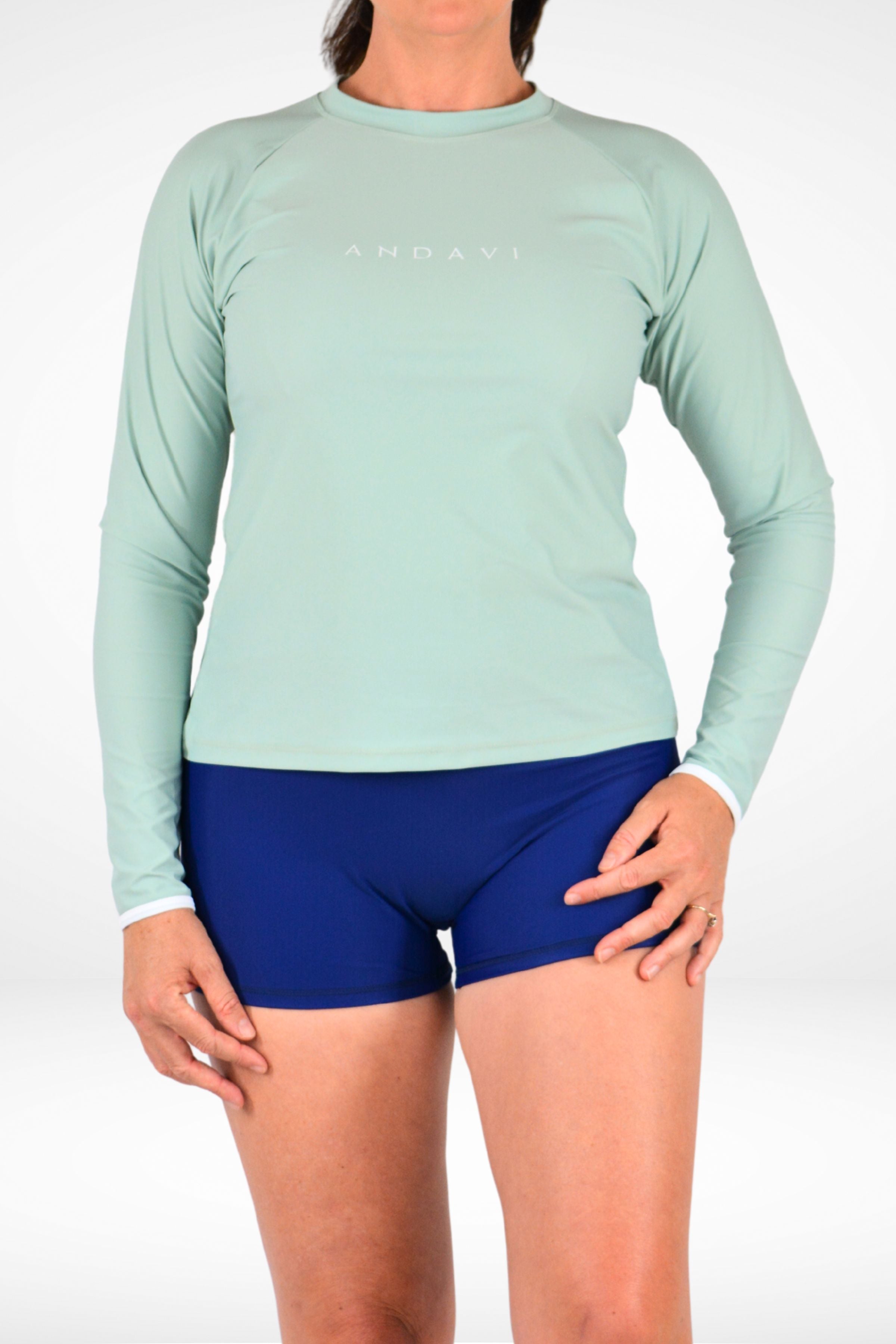 Person wearing a light green long-sleeve shirt and blue shorts on a white background