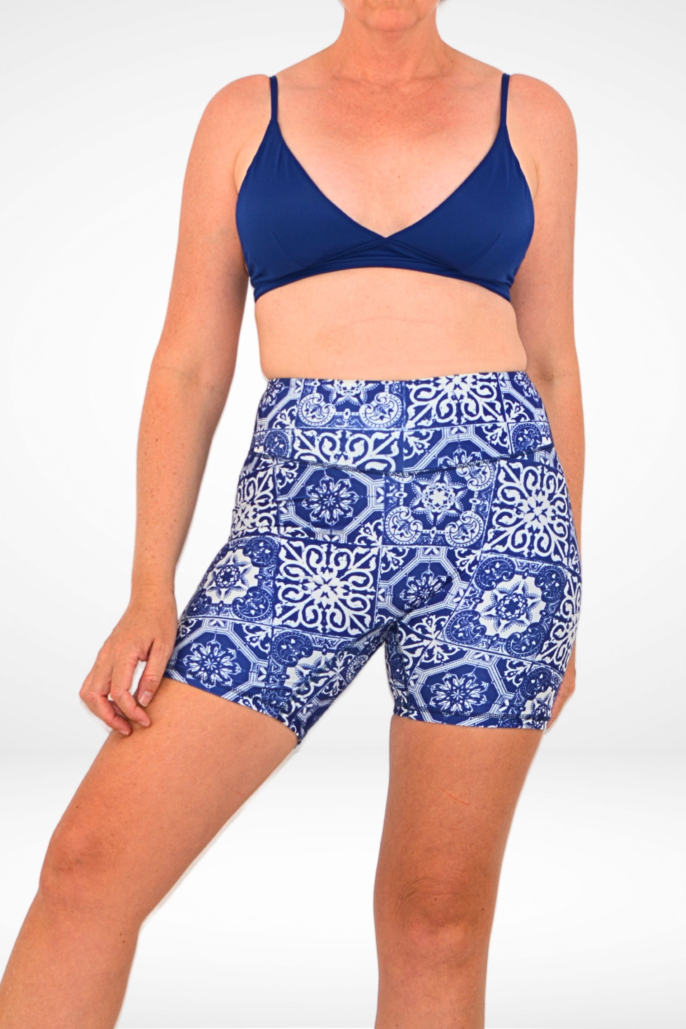 model wearing navy blue triangle bikini top and navy blue and white geometric print swim active shorts