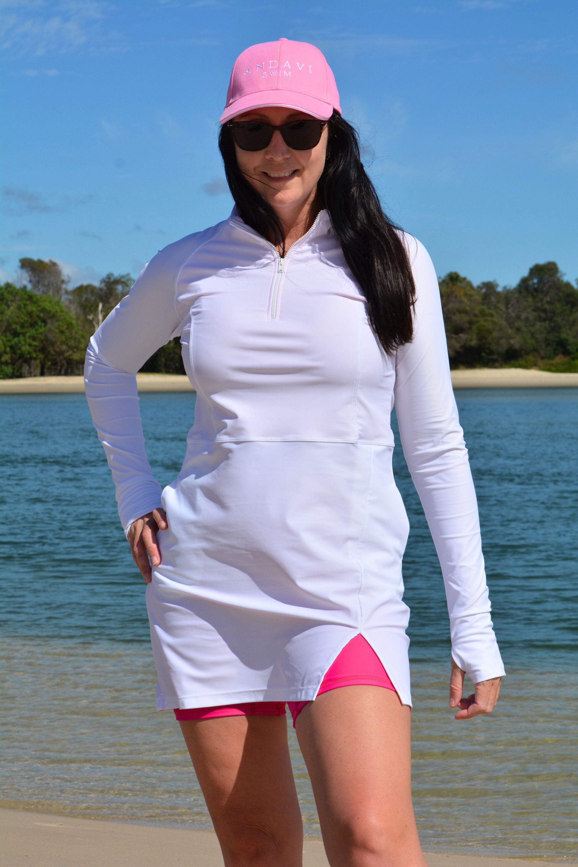 model wearing andavi swim hot pink swim shorts and white long sleeve andavi swim rash guard and matching hot pink andavi swim pink cap
