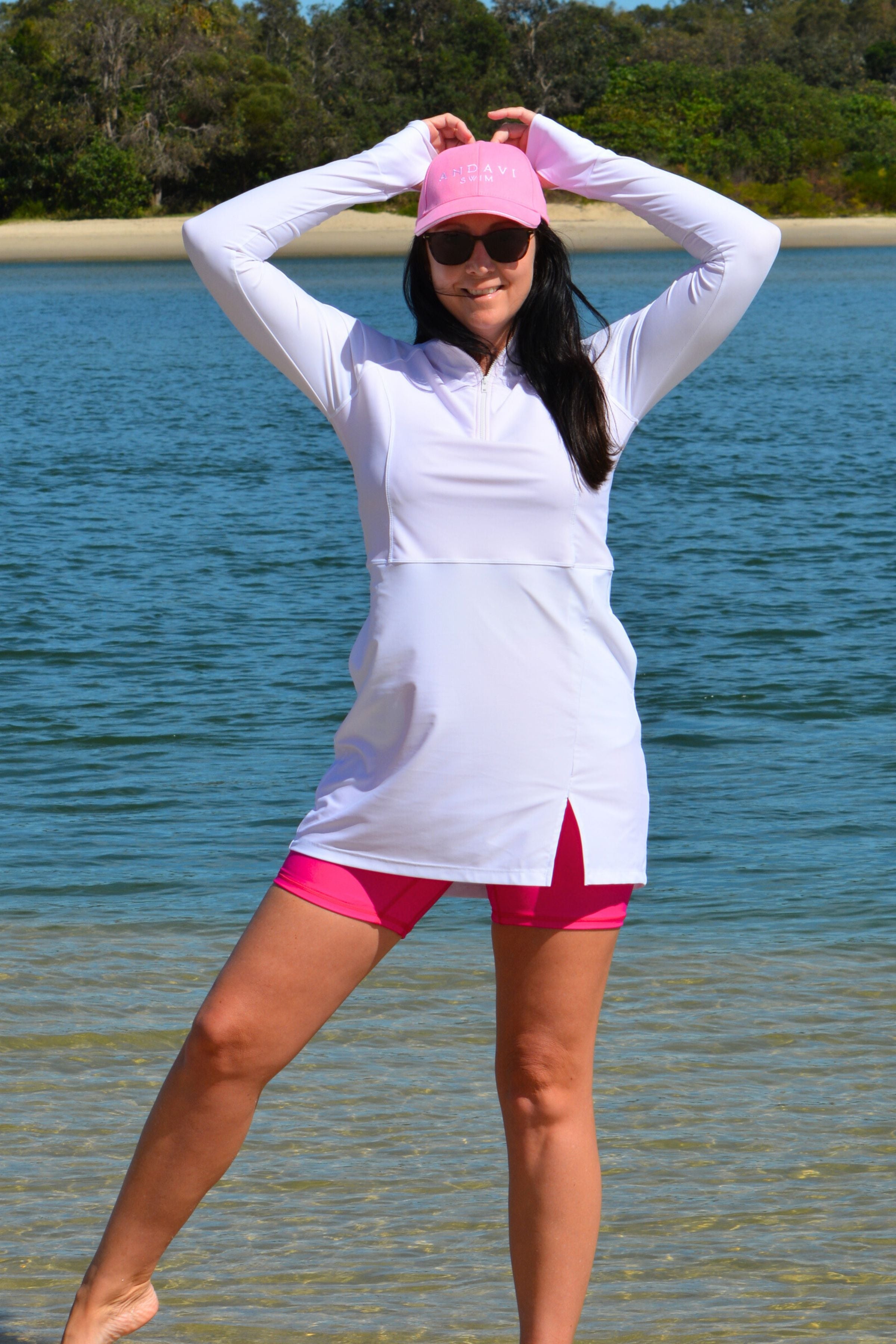 model wearing andavi swim hot pink swim shorts and white long sleeve andavi swim rash guard and matching hot pink andavi swim pink cap