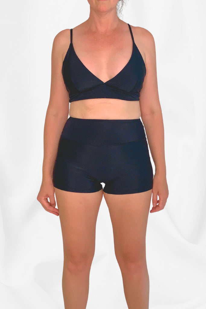 model wearing black triangle bikini top and black swim shorts