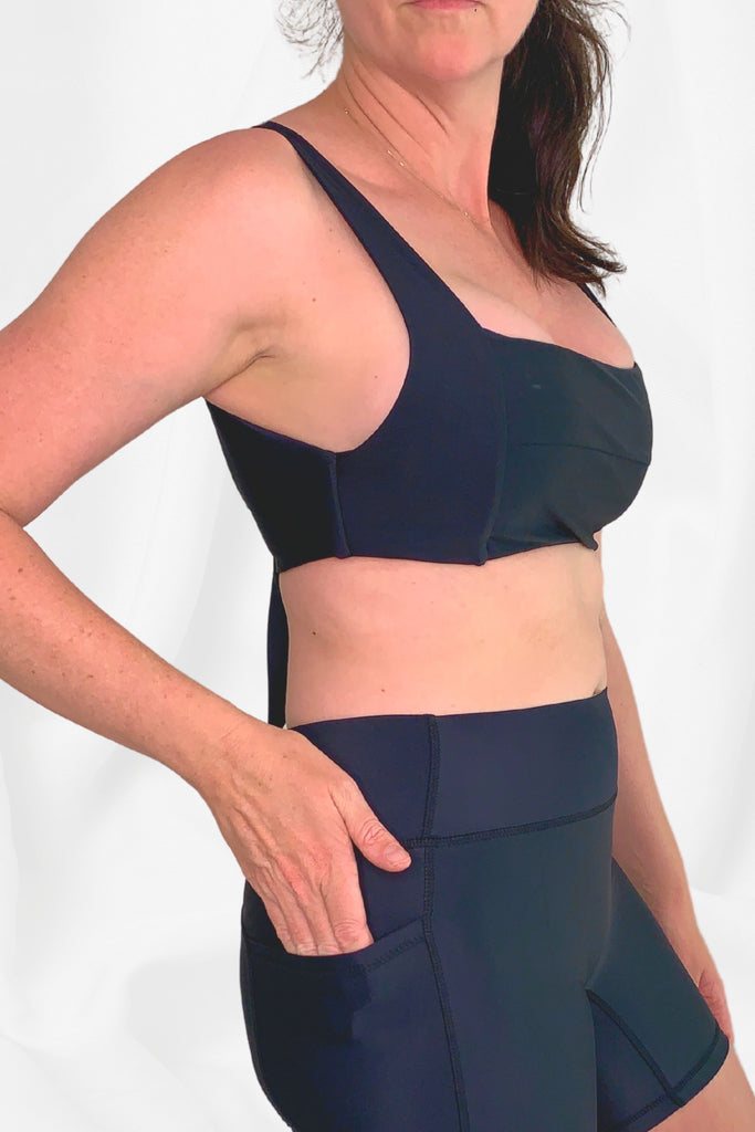 model facing side on wearing a black square neck bikini top and black swim active bike shorts