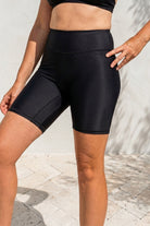 Person wearing black athletic shorts on a light background