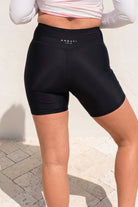 Person wearing black athletic shorts with a brand logo on a light background
