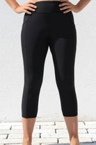 Person wearing black capri leggings against a light gray background