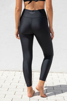 Person wearing black swim leggings with a visible brand logo against a white background
