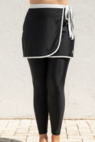 Black athletic swim skirt and swim leggings set with white trim against a light background