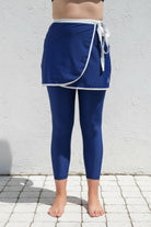 Person wearing a blue swim active skirt and leggings against a white wall.