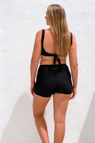 Woman wearing a black bikini set with a white background