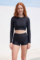 women wearing andavi long sleeve crop black rash guard in black and black swim shorts