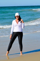 women on the beach wearing white rash guard and black sun protection swim leggings