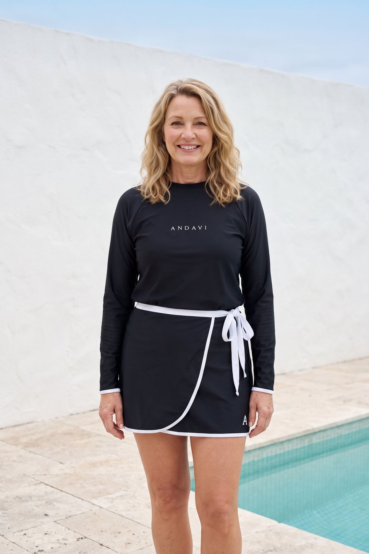 women standing front on wearing andavi long sleeve black rash guard and black with white trim andavi swim wrap skirt