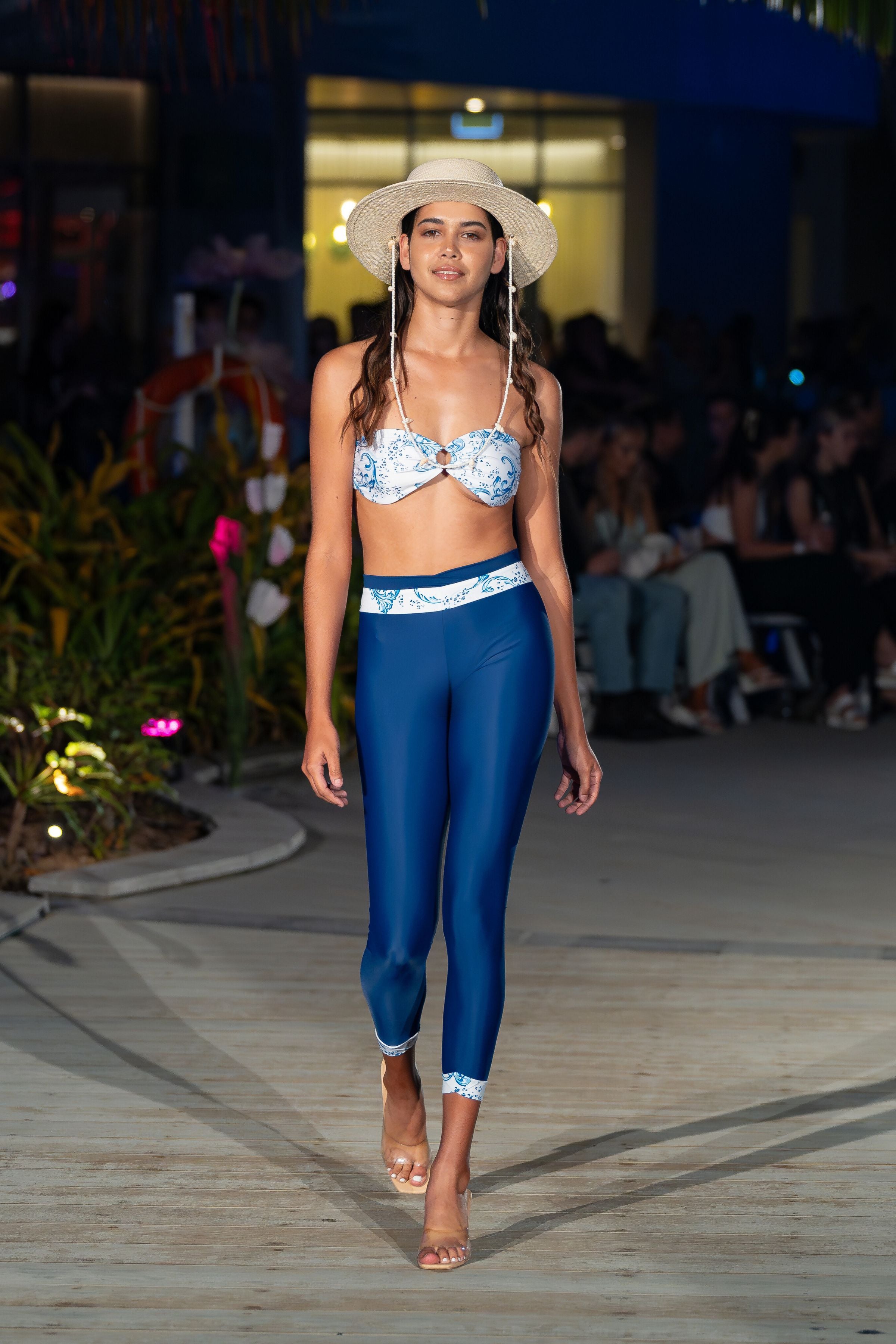 women on catwalk wearing straw hat white and blue bikini top and leggings