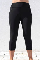 Black capri leggings worn by a person against a light gray background