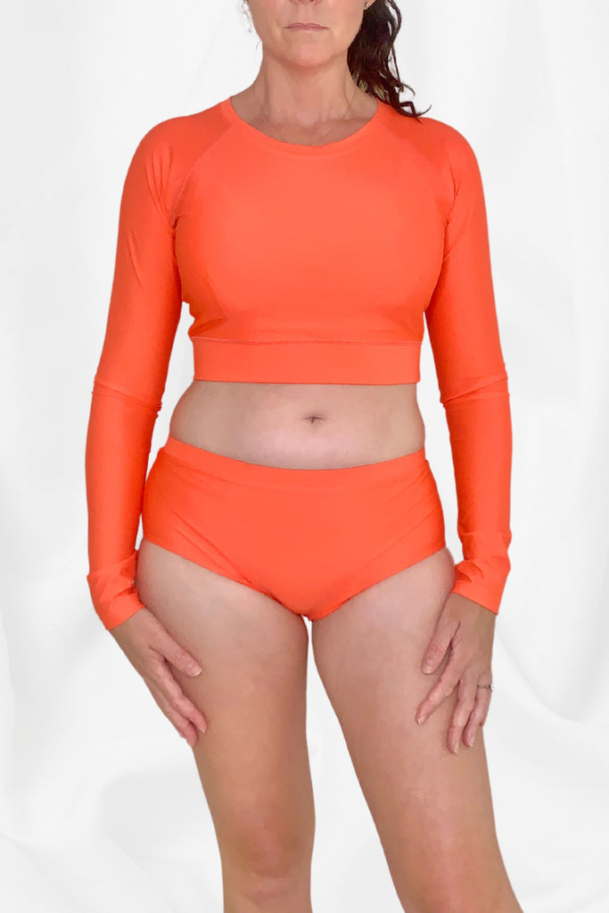 women wearing coral rash guard and bikini bottom