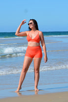 women on the beach wearing orange coral swim shorties and triangle bikini top