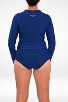 model wearing andavi dark blue full coverage bikini bottom and matching dark blue long sleeve rash guard