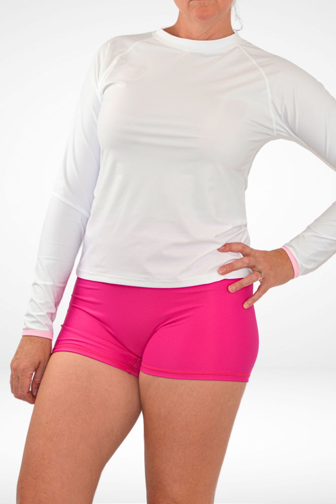 side on view of model wearing pink swim active shorties and white rash guard