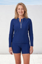 Woman wearing a dark blue long-sleeve top and shorts set against a white background