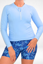 women wearing light blue half zip long sleeve rash gaurd and white and blue print swim active bike shorts