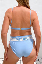 Light blue bikini with floral patterned waistband on a white background