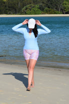 women on the beach wearing white hat and light blue long sleeve rash guard with floral bike shors