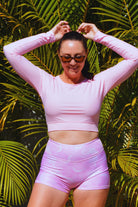 women wearing light pink crop rash guard and pink patter swim shorts 