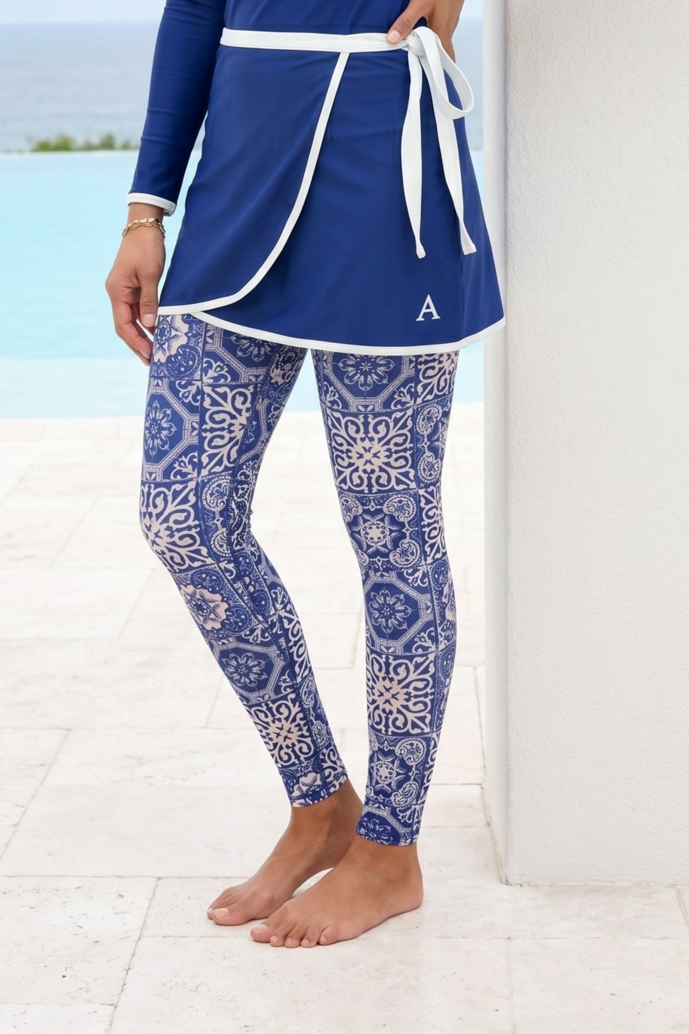 Person wearing a blue outfit with a patterned design by a poolside.