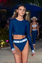 women on catwalk wearing navy blue crop rash guard and navy blue white bikini bottom