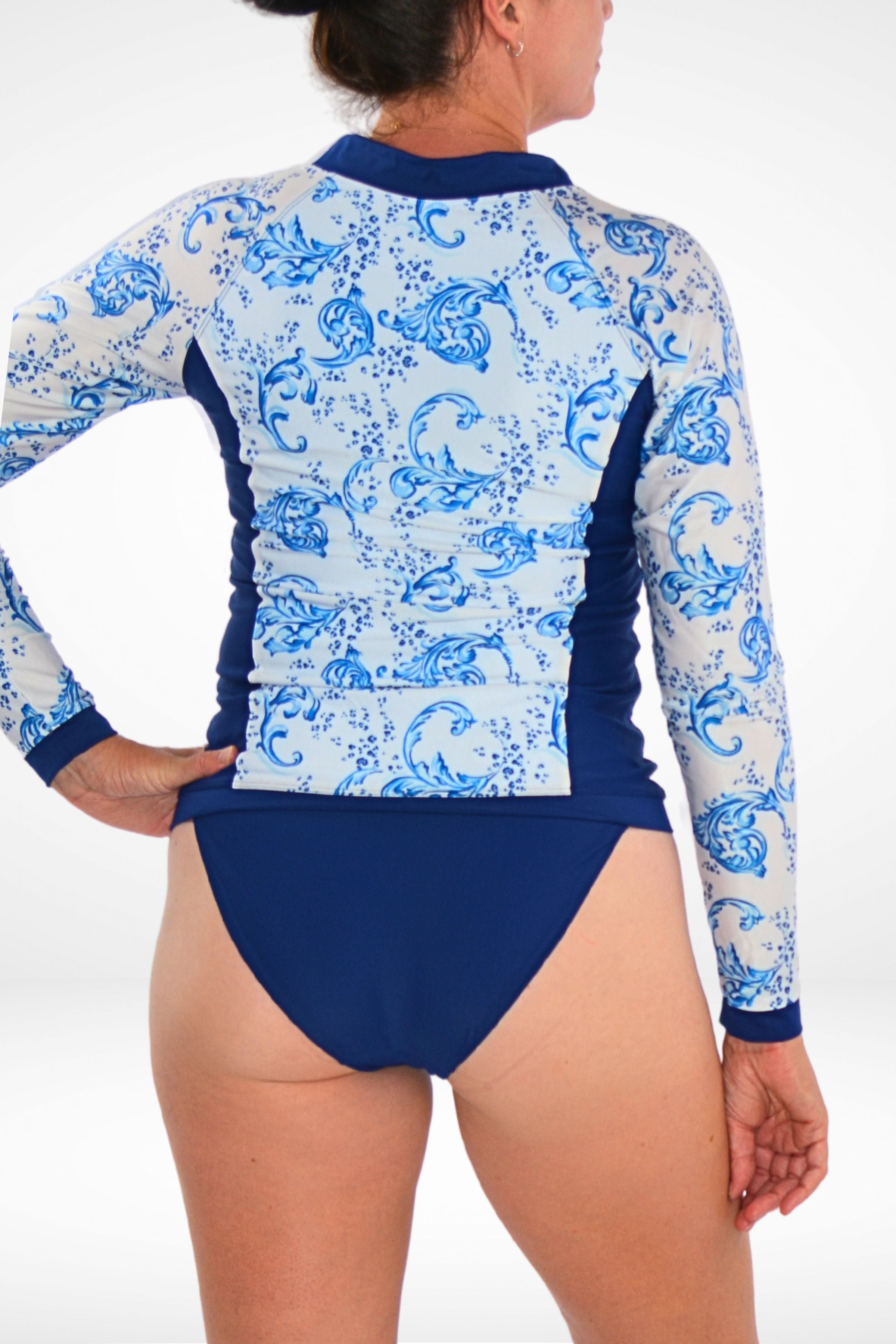 women wearing navy blue bikini bottom and long sleeve white and blue animal print rash guard 