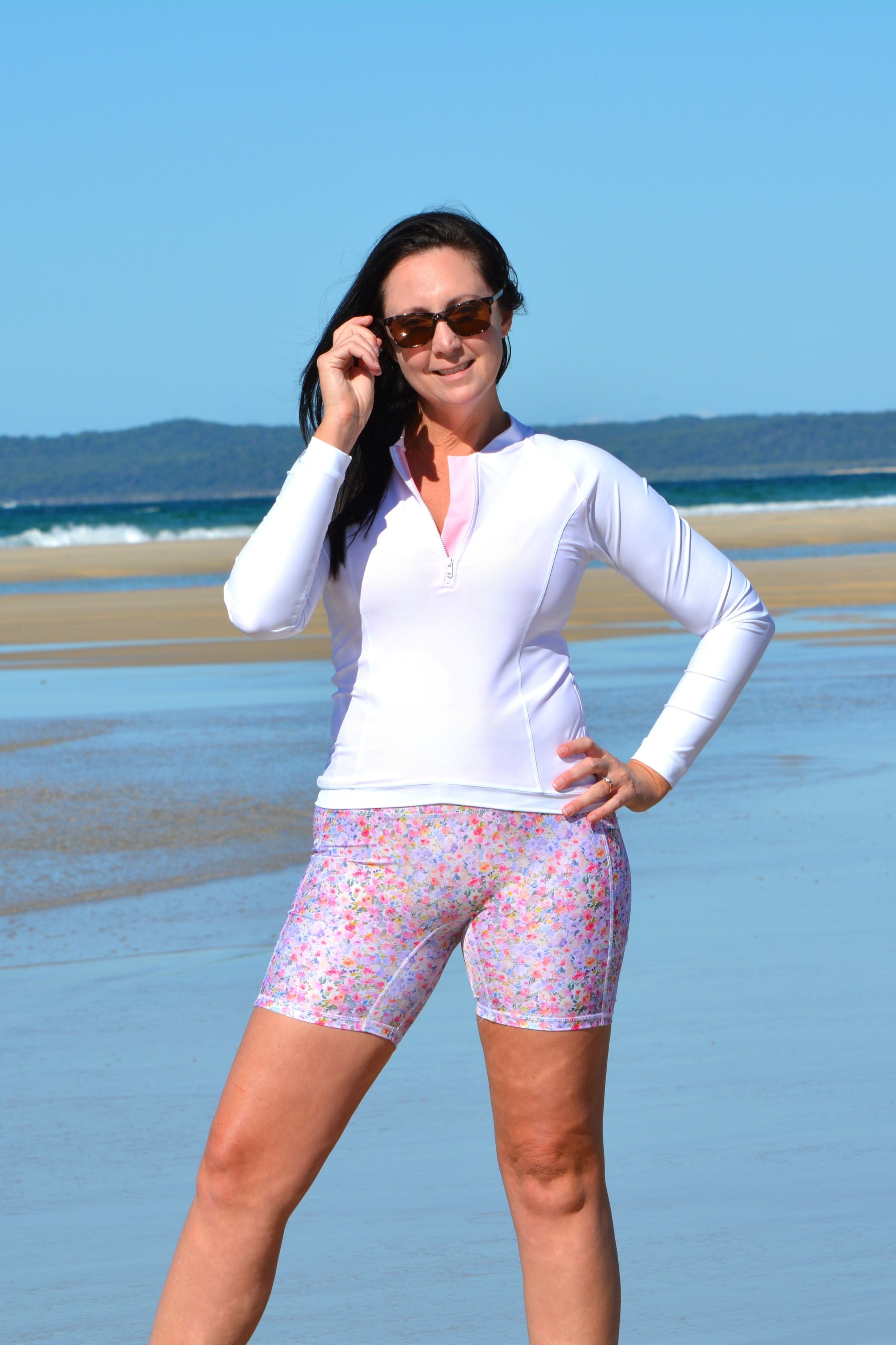 women on the beach wearing long sleeve Andavi white rashie and floral pocket bike shorts