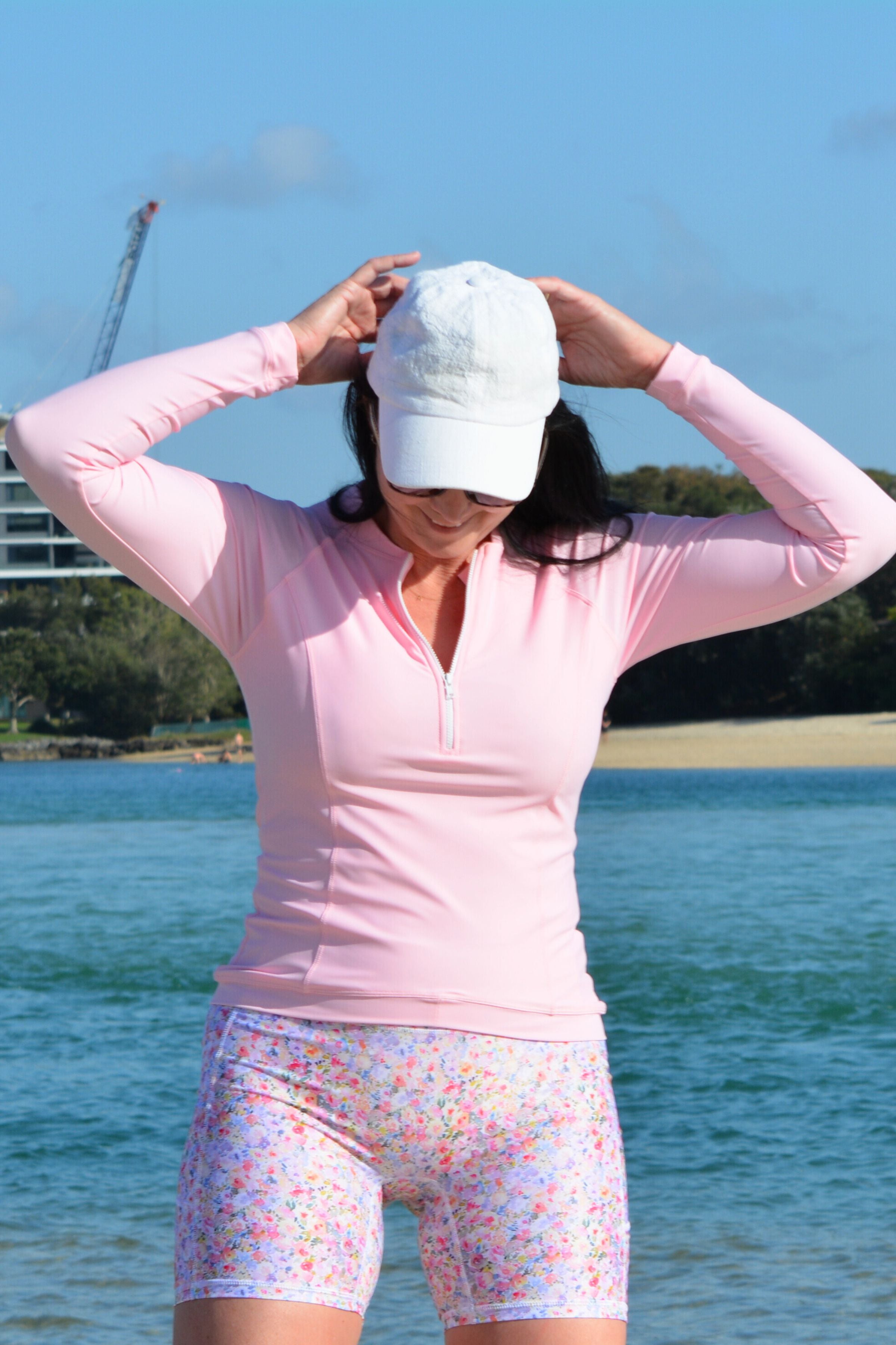 women at the beach wearing light pink long sleeve rash guard and floral swim active shorts