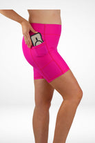 Person wearing bright pink swim shorts with a pocket on a white background