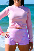 women wearing Andavi pink long sleeve rash guard and pink and white print swim shorts