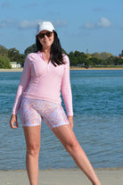 women standing at the beach wearing light pink long sleeve rash guard and floral bike pants