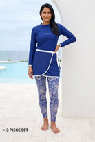 Woman wearing a blue Rash Guard and patterned leggings by a pool.