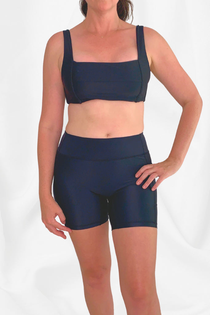 model wearing black square neck bikini top and black swim bike shorts