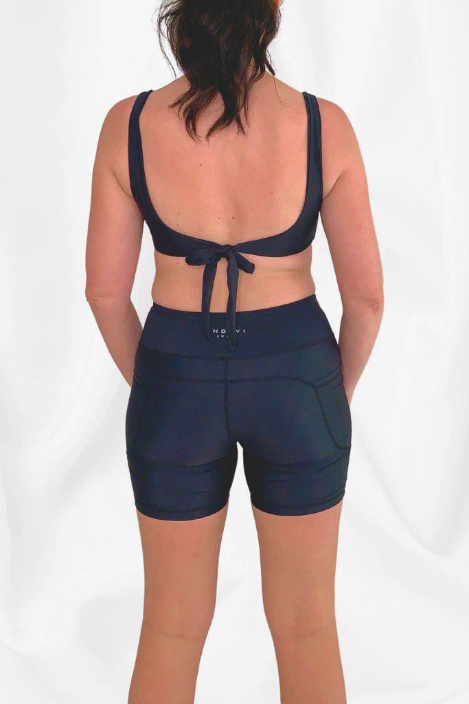 back view of model wearing black tie up bikini top and black swim bike shorts Andavi Swim logo