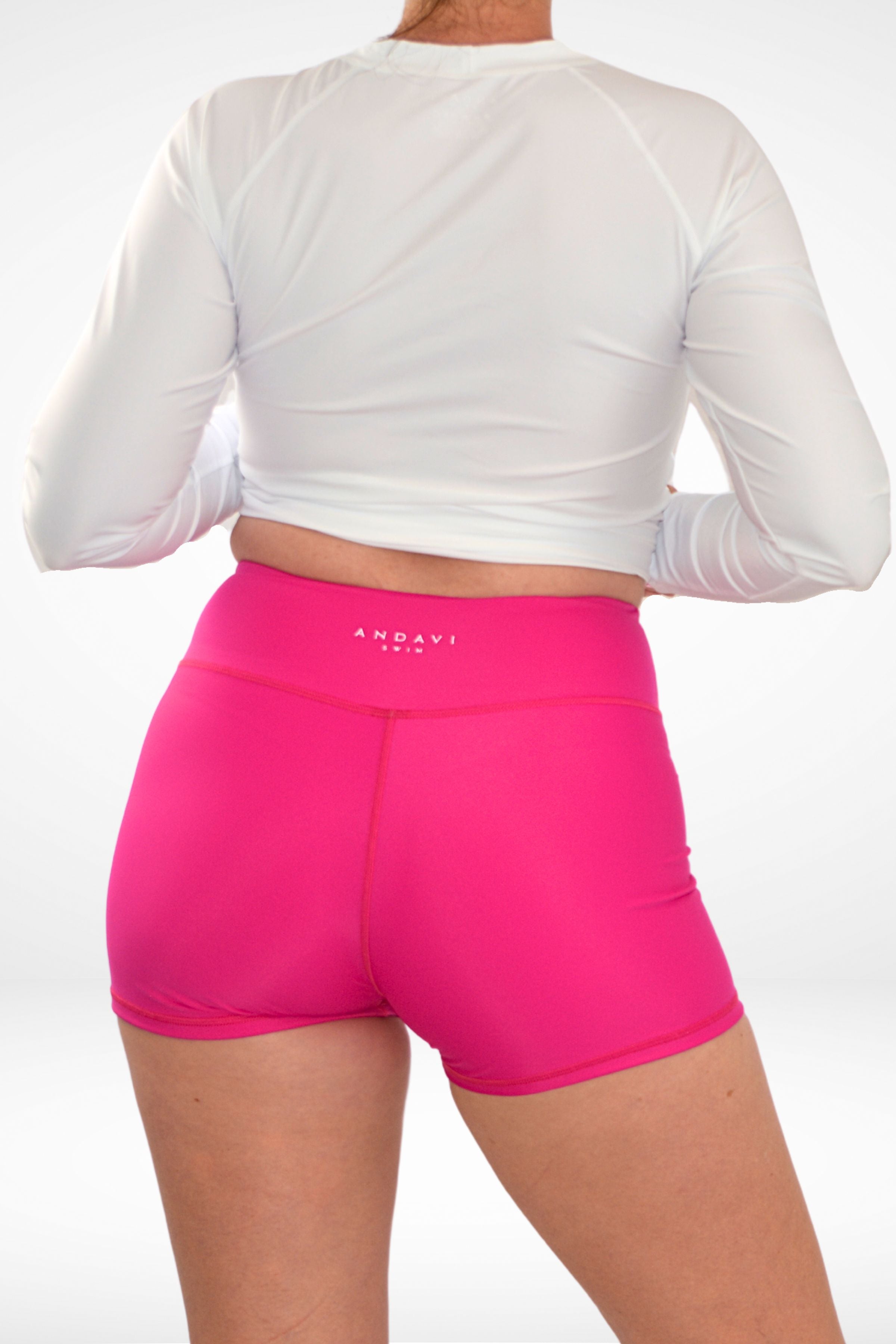 the back view of a model wearing Andavi Swim pink swim active shorties and white rash guard