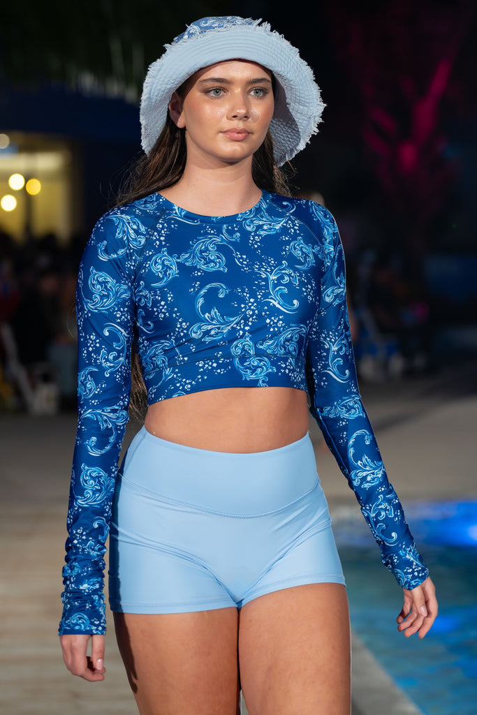 women wearing light blue shorts and blue and white long sleeve crop rash guard with bucket hat
